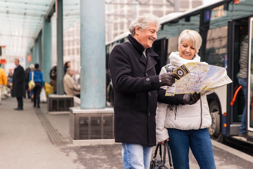 Aurélien Bergot's photograph for Geneva Public Transport featuring a man and a woman dressed in winter outerwear standing outside of a bus and smiling while consulting a map.